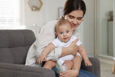 Photo of Happy young mother with her baby in armchair at home