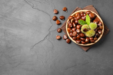 Photo of Fresh sweet edible chestnuts on black slate table, flat lay. Space for text