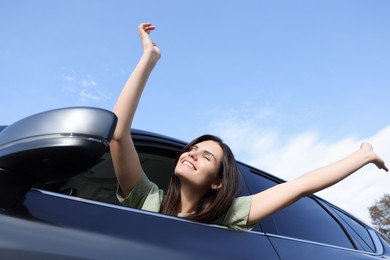 Photo of Beautiful young woman raising arms from car window