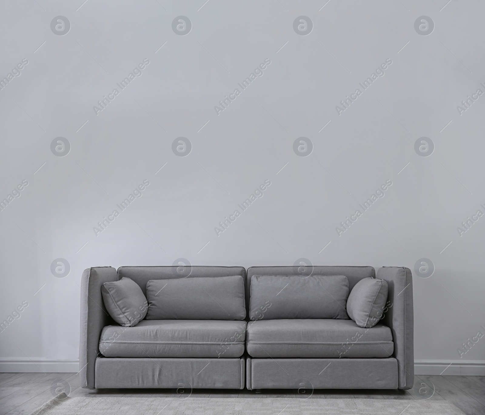 Photo of Simple living room interior with comfortable sofa near light wall. Space for text