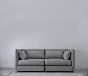 Photo of Simple living room interior with comfortable sofa near light wall. Space for text