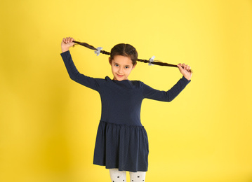 Portrait of cute little girl on yellow background