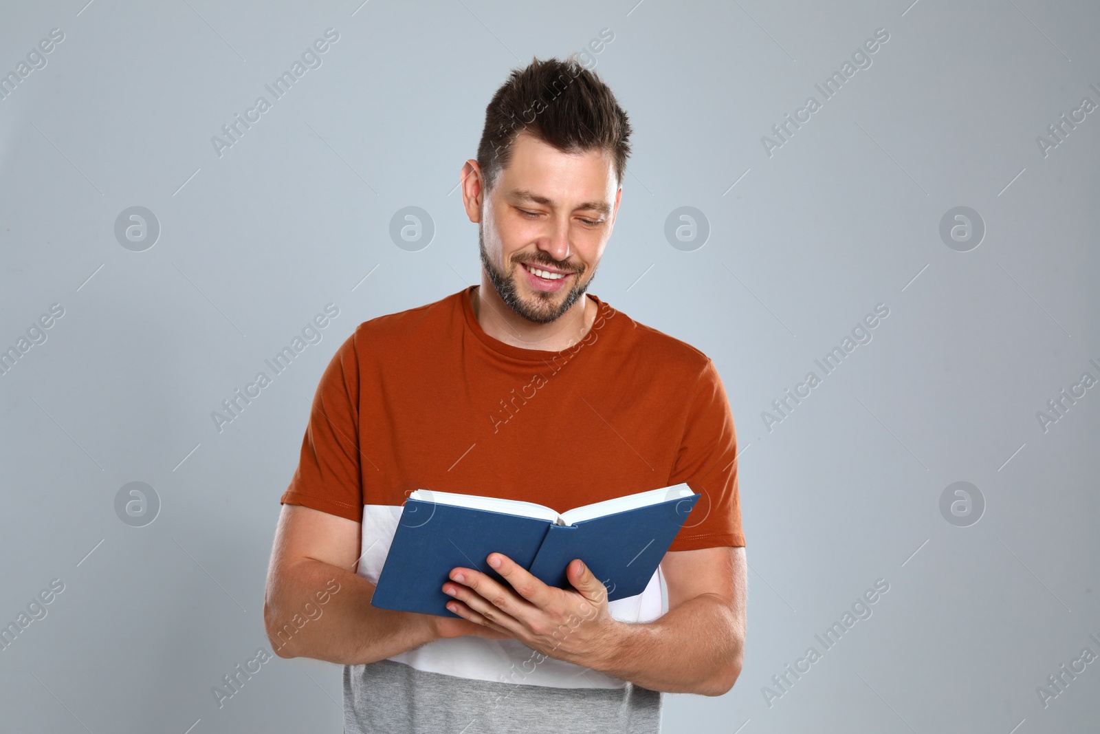 Photo of Handsome man reading book on light background