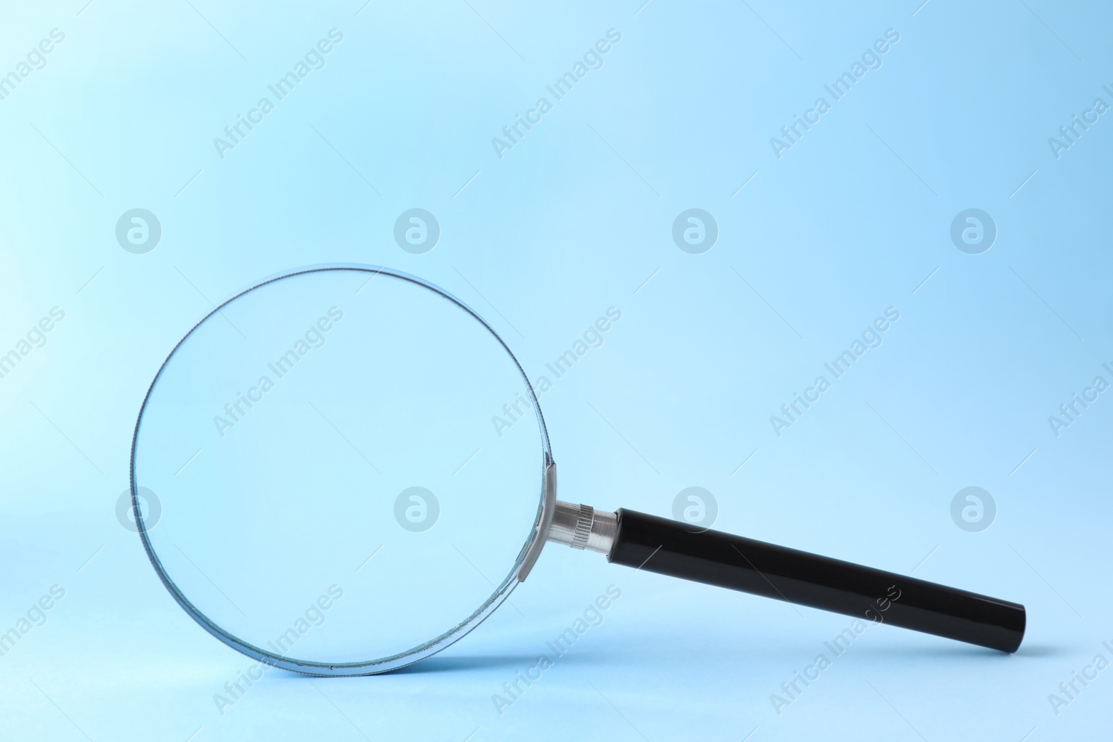 Photo of Magnifying glass with handle on light blue background