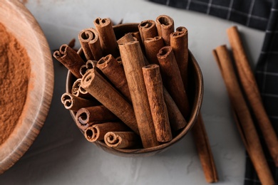 Bowl with aromatic cinnamon sticks on table