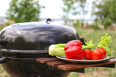 Plate with vegetables near barbecue grill outdoors, closeup