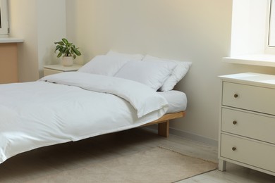 Bed with soft white pillows in cozy room interior