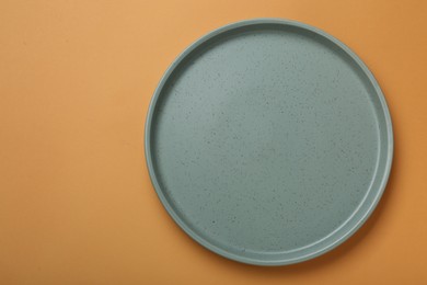 Empty ceramic plate on pale orange background, top view. Space for text