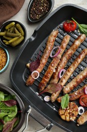 Photo of Grill pan with tasty sausages, spices and vegetables on light table, flat lay