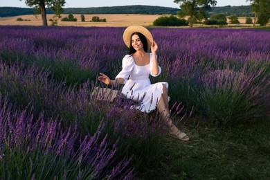 Photo of Beautiful young woman sitting in lavender field