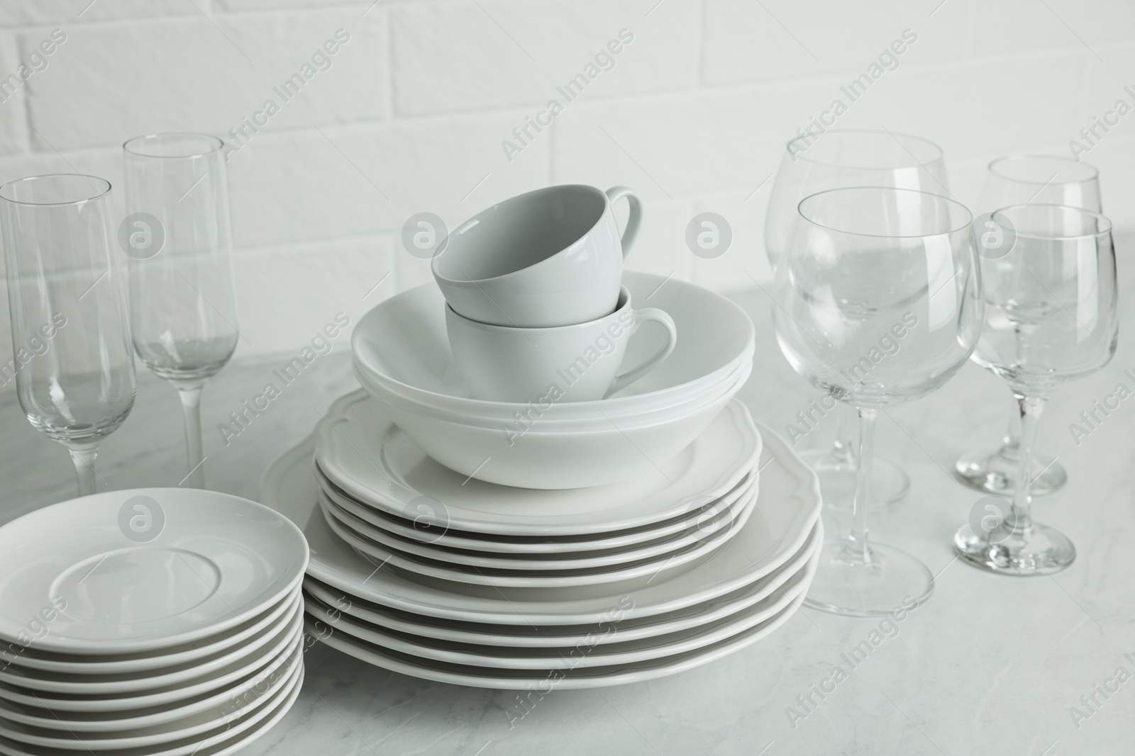 Photo of Different clean dishware, cups and glasses on countertop
