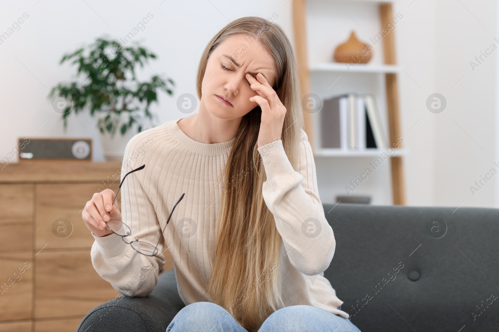 Photo of Overwhelmed young woman with glasses suffering from headache at home