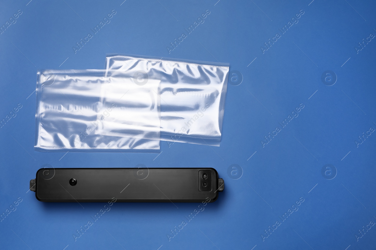 Photo of Sealer for vacuum packing with plastic bags on blue background, flat lay. Space for text