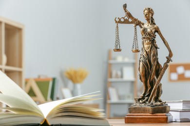 Figure of Lady Justice and books on table indoors, space for text. Symbol of fair treatment under law