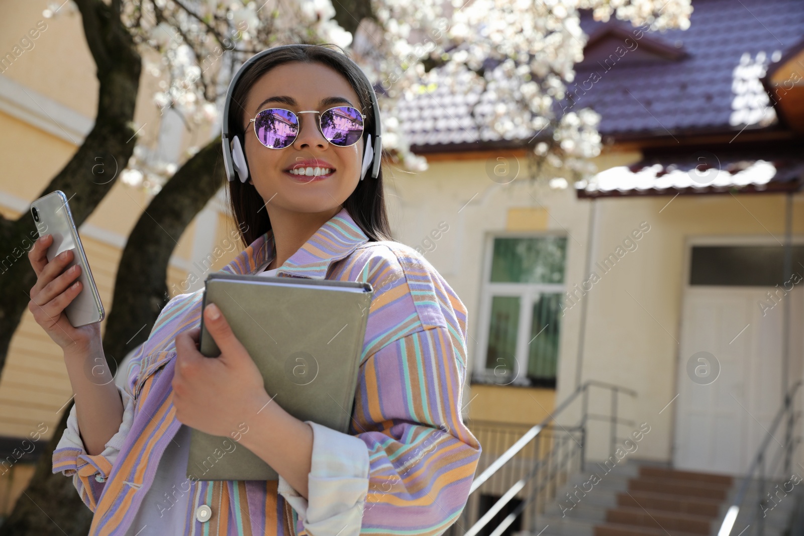 Photo of Young woman listening to audiobook on city street