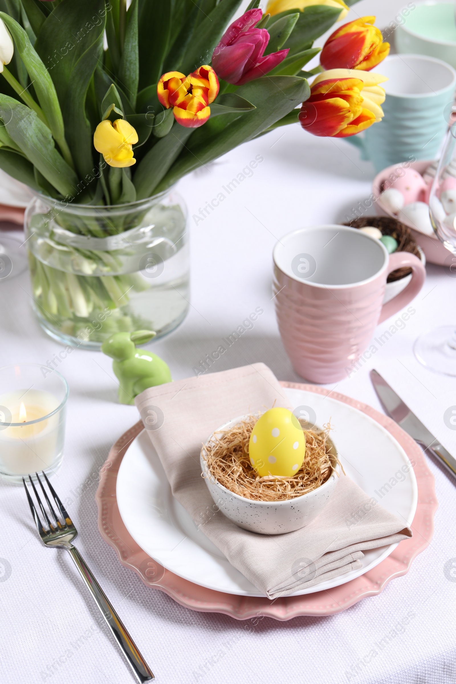 Photo of Festive table setting with painted egg in decorative nest. Easter celebration