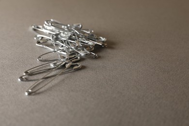 Safety pins on grey textured background, closeup. Space for text