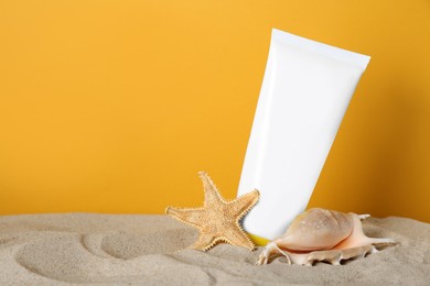 Photo of Suntan product, seashell and starfish on sand against yellow background. Space for text