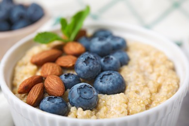 Photo of Bowl of delicious cooked quinoa with almonds and blueberries, closeup