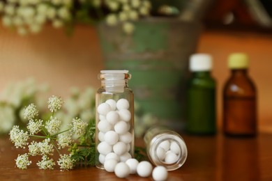Bottles with homeopathic remedy and flowers on table