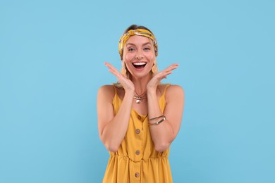 Portrait of happy hippie woman on light blue background