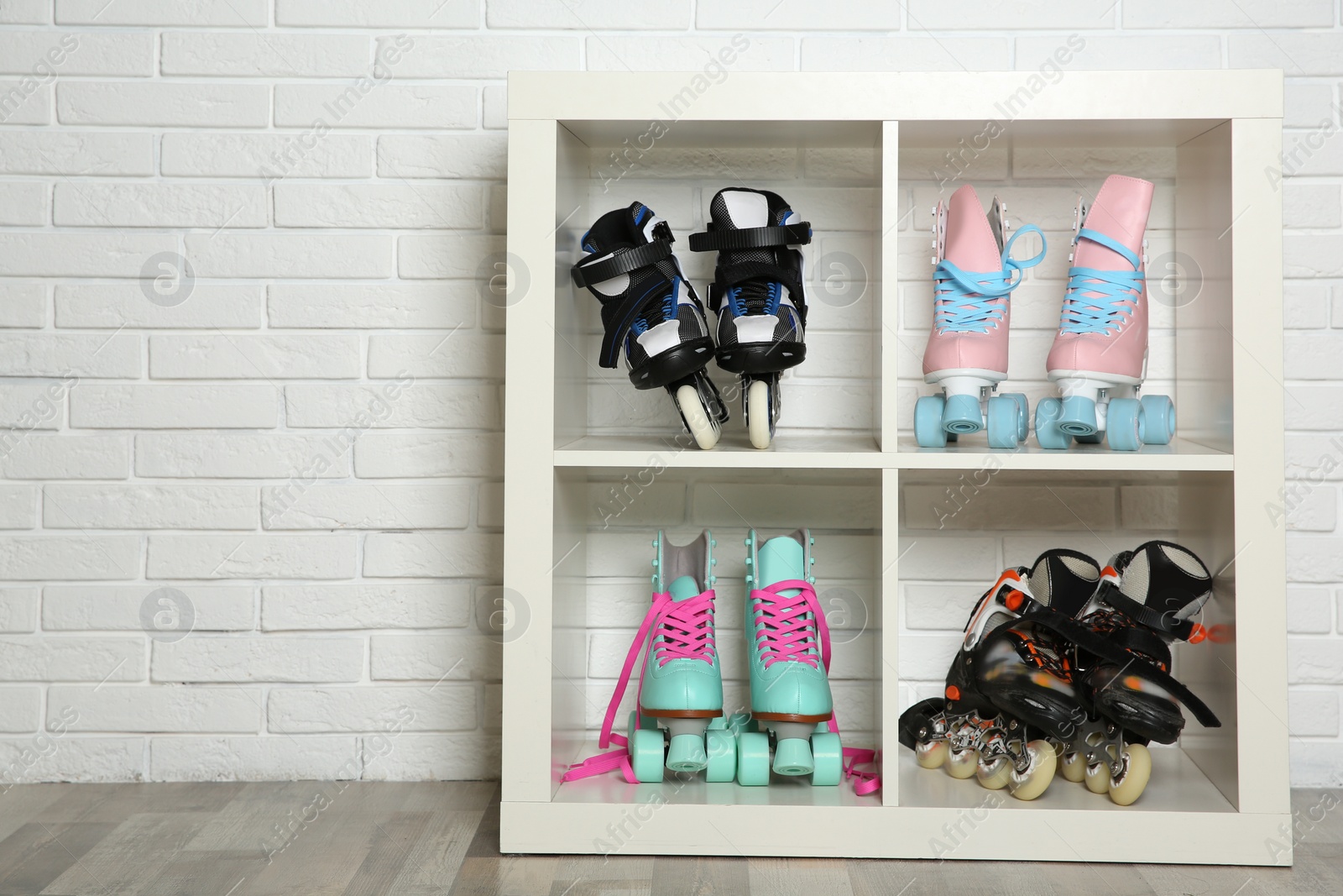 Photo of Pairs of roller skates on shelves near white brick wall. Space for text