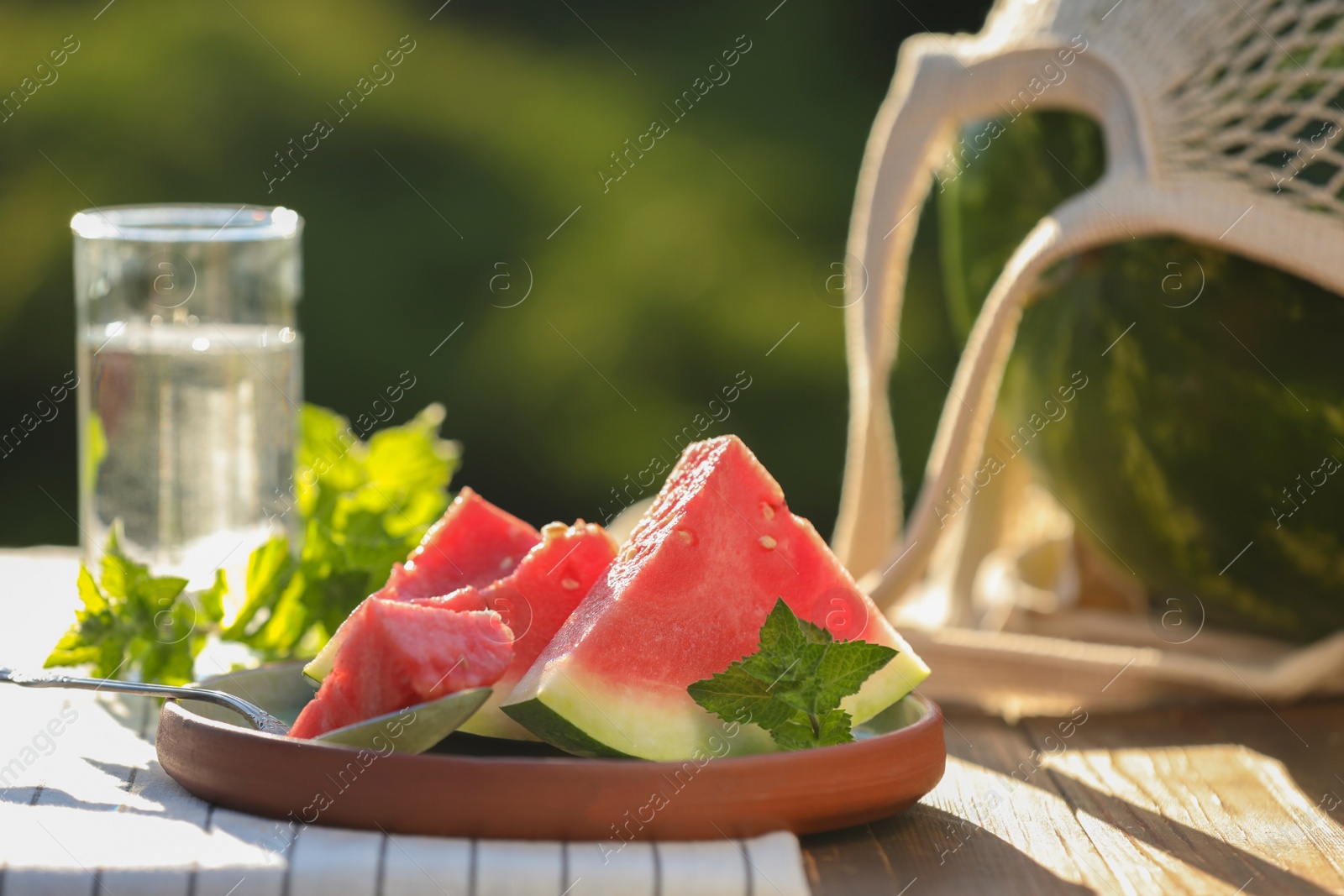 Photo of Slices of tasty ripe watermelon on wooden table outdoors