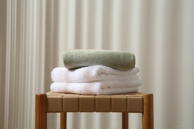 Photo of Stack of soft towels on wicker bench indoors, closeup