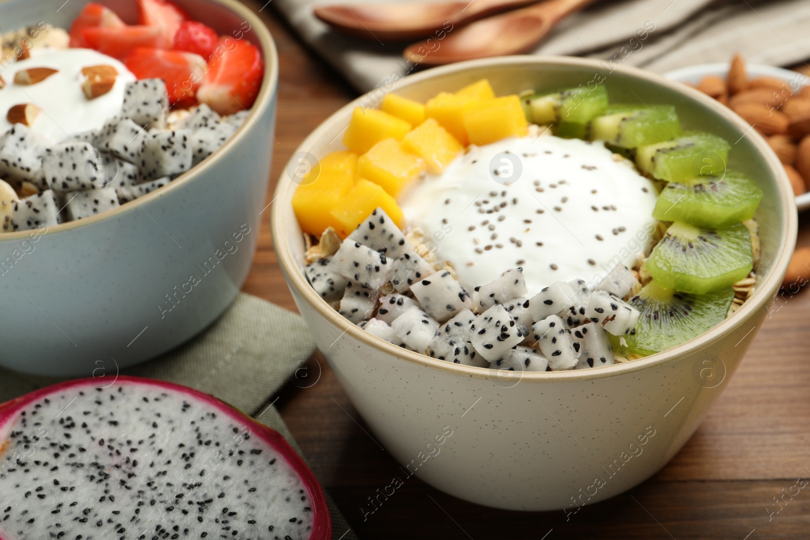 Photo of Bowls of granola with yogurt and fruits on wooden table