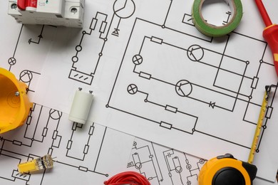 Photo of Different electrician's equipment on wiring diagrams, flat lay