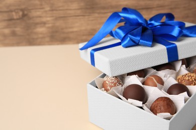 Photo of Box with delicious chocolate candies on beige background, closeup. Space for text