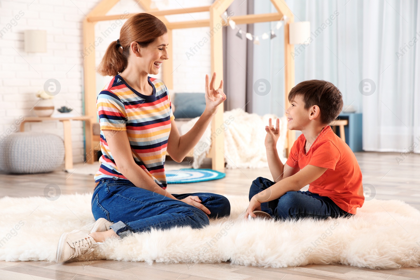 Photo of Hearing impaired mother and her child talking with help of sign language indoors