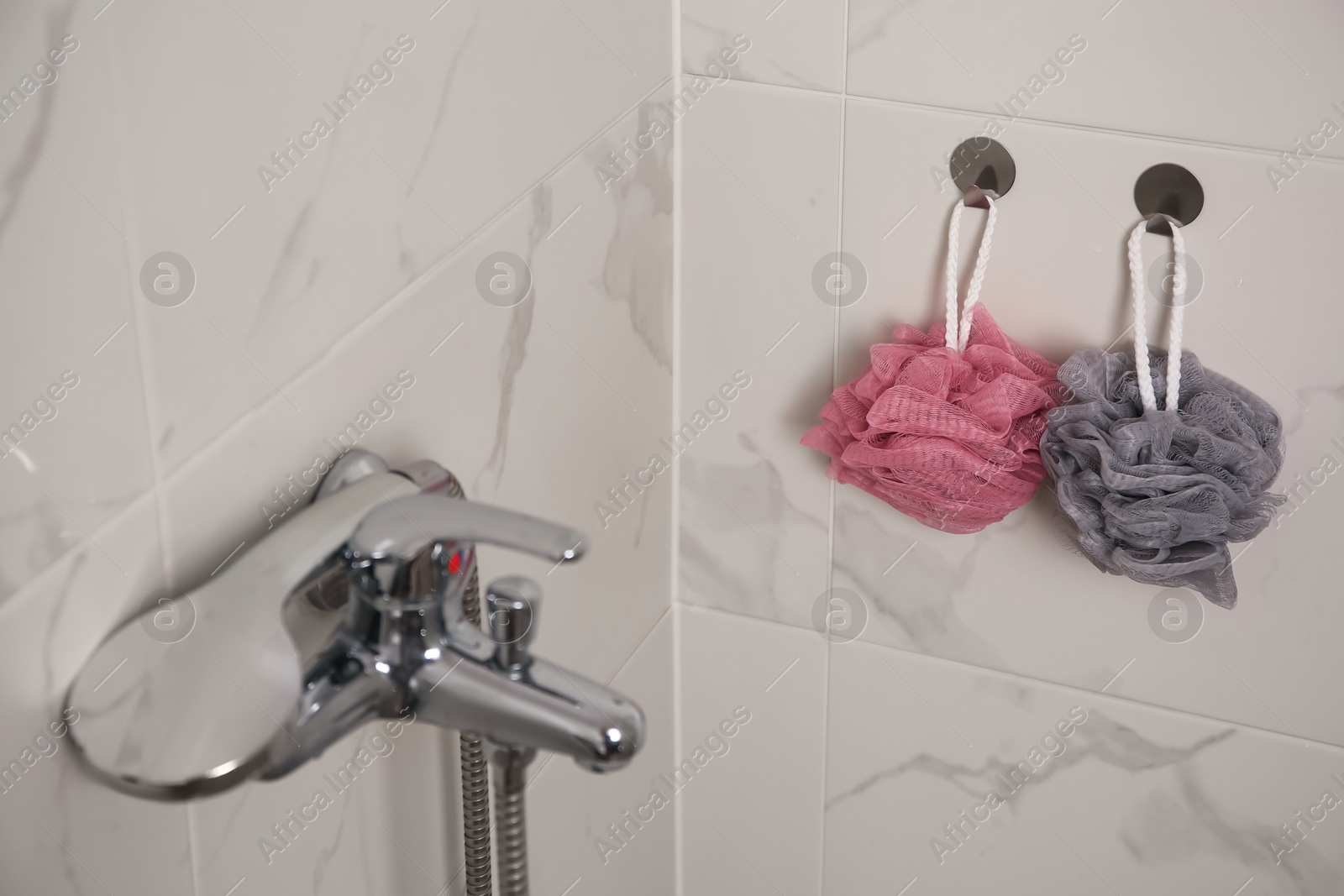 Photo of Shower puffs hanging near faucet in bathroom, space for text