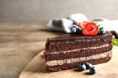 Photo of Delicious fresh chocolate cake with berries on wooden table