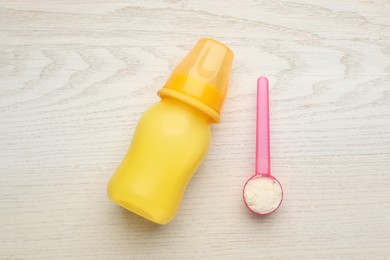 Photo of Feeding bottle with infant formula and powder on white wooden table, flat lay