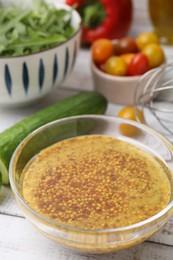 Photo of Tasty vinegar based sauce (Vinaigrette) in bowl and products on wooden rustic table, closeup