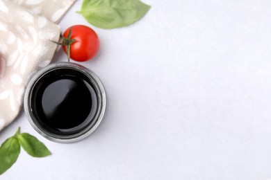 Balsamic vinegar, basil and tomato on white table, flat lay. Space for text