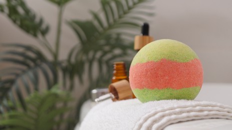 Photo of Towel with bath bomb and bottles of essential oils on tub indoors, closeup. Space for text