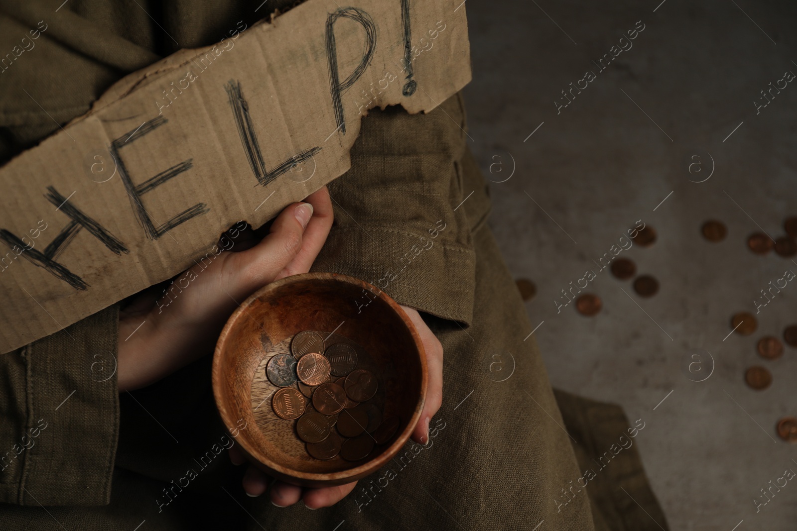 Photo of Poor homeless woman with help sign holding bowl of donations on floor, closeup. Space for text