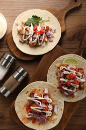 Photo of Delicious tacos with vegetables, meat and sauce on wooden table, flat lay