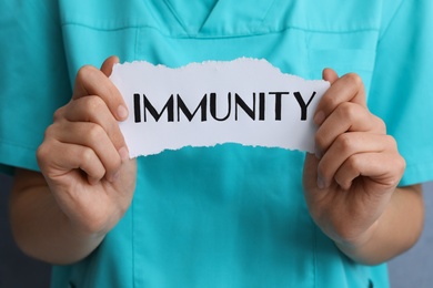 Woman holding paper piece with word Immunity, closeup