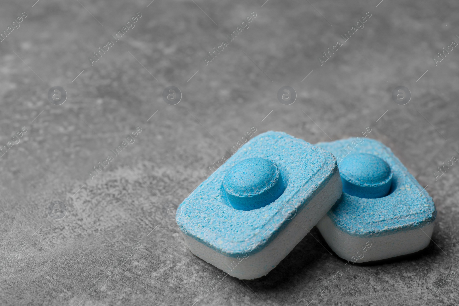 Photo of Water softener tablets on grey table, closeup. Space for text