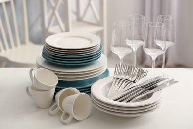 Photo of Set of clean dishware, cutlery and wineglasses on white table indoors