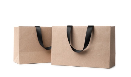 Photo of Paper shopping bags with ribbon handles on white background. Mockup for design