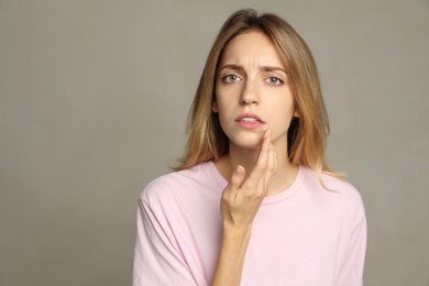 Photo of Woman with herpes applying cream onto lip against  light grey background