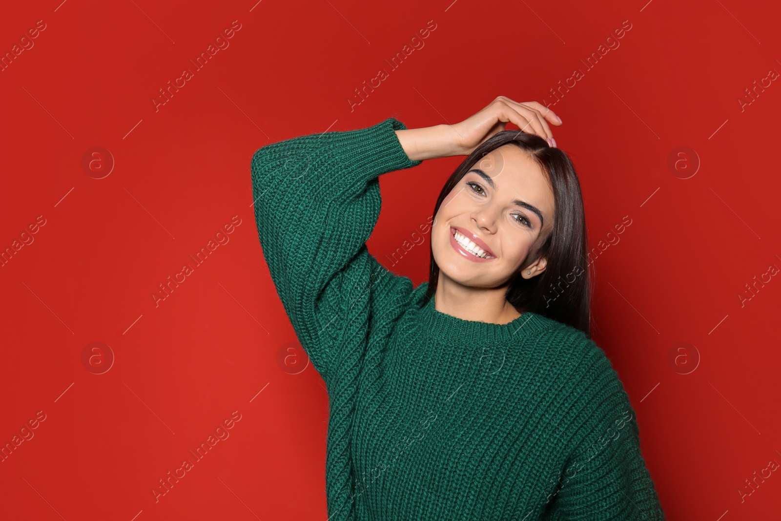 Image of Happy young woman wearing warm sweater on red background 