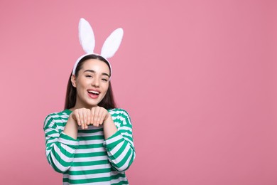 Photo of Happy woman wearing bunny ears headband on pink background, space for text. Easter celebration