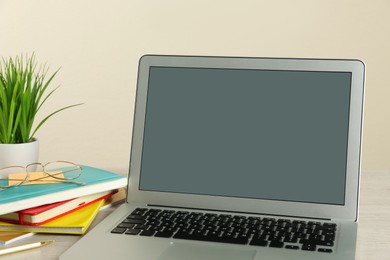 Modern laptop and office supplies on wooden table. Distance learning