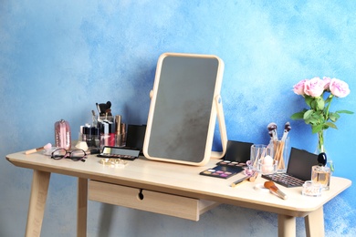Dressing table with beauty accessories near color wall in room