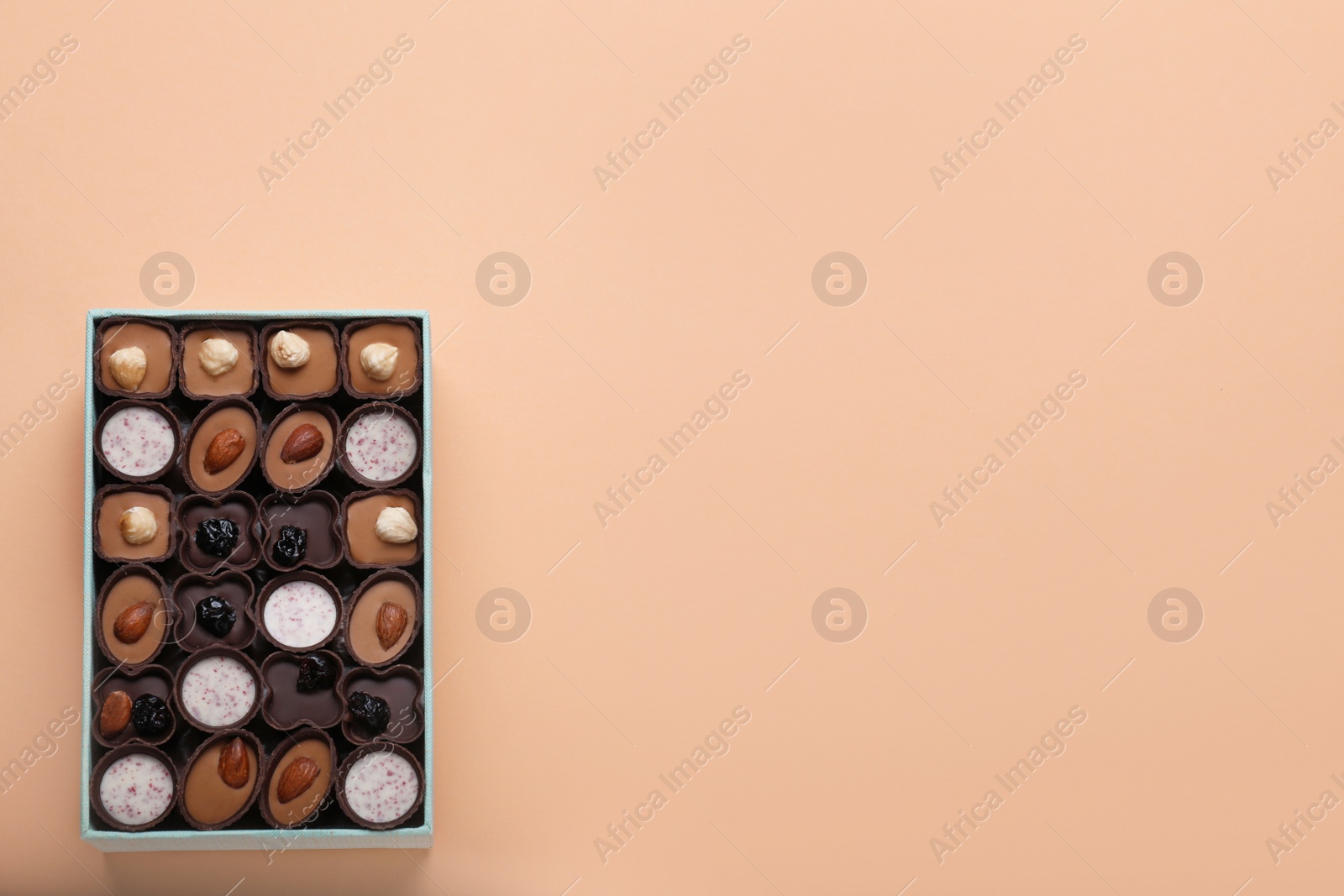 Photo of Box of delicious chocolate candies on beige background, top view. Space for text